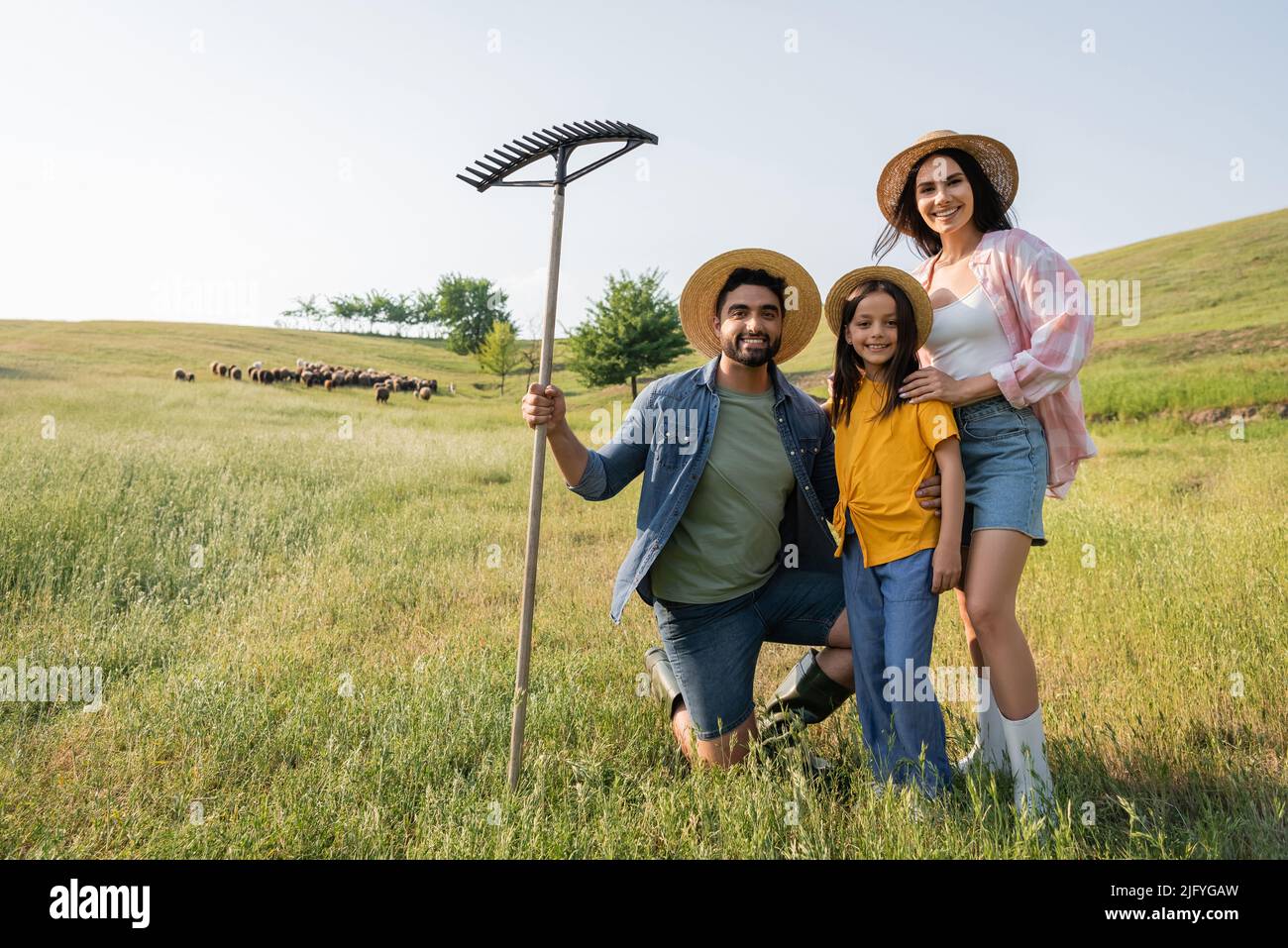 famille de ferme heureuse regardant la caméra près d'un troupeau pâturage dans un pré pittoresque Banque D'Images