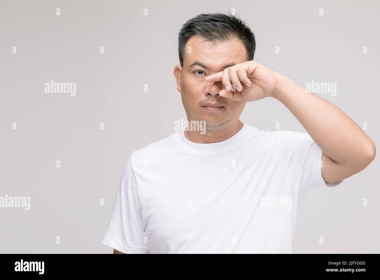 Concept d'irritation des yeux : Portrait de l'homme asiatique en posture de fatigue oculaire, irritation ou problème oculaire. Prise de vue en studio isolée sur fond gris Banque D'Images