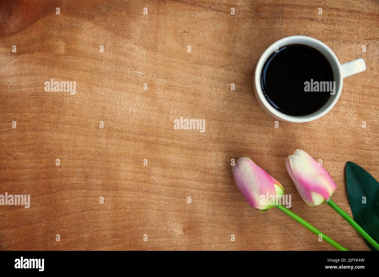 Vue de dessus d'une tasse à café avec fleur rose sur fond de table en bois. Espace de travail et de copie Banque D'Images