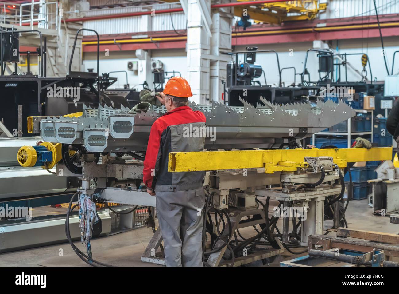 Travailleur en cours de montage de composants pour la production de moissonneuses-batteuses ou de tracteurs sur la chaîne de production industrielle. Banque D'Images