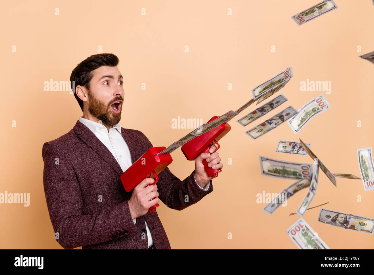 Photo de jeune choqué surpris homme d'affaires surpris avec l'argent pistolet voir promotion shopping isolé sur fond beige couleur Banque D'Images
