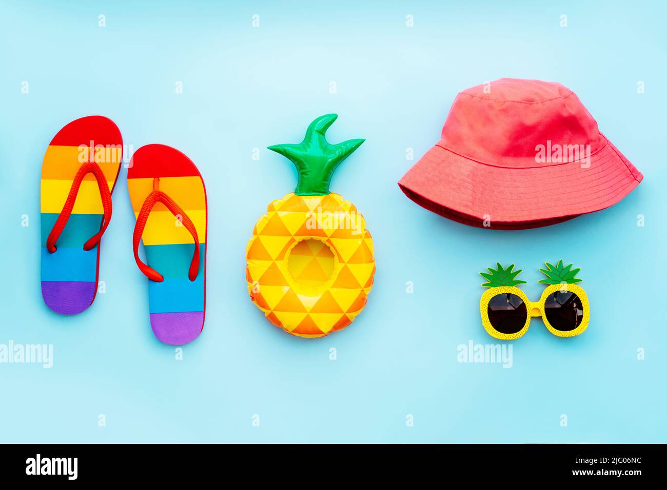 Vue du haut concept de vacances d'été à la plage ou à la piscine avec tongs de couleur arc-en-ciel, porte-gobelet gonflable à l'ananas, chapeau de seau rose et lunettes de soleil drôles Banque D'Images Vue du haut concept de vacances d'été à la plage ou à la piscine avec tongs de couleur arc-en-ciel, porte-gobelet gonflable à l'ananas, chapeau de seau rose et lunettes de soleil drôles Banque D'Images