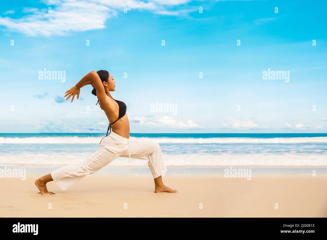 Femme pratiquant le yoga au bord de mer de la plage tropique, femme sportive debout à la plage faire des exercices de yoga Banque D'Images