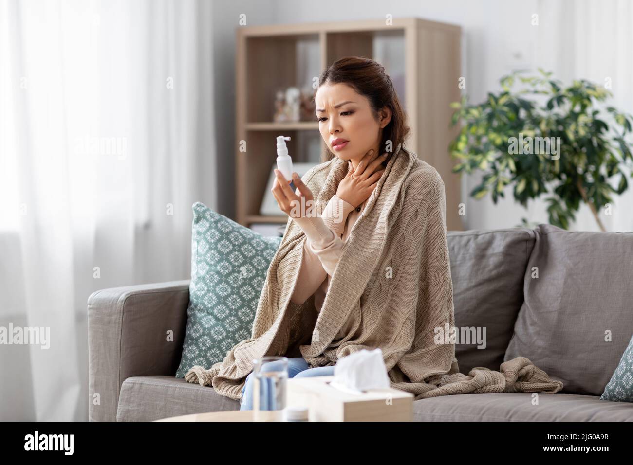 femme asiatique malade avec un traitement par pulvérisation orale à la maison Banque D'Images