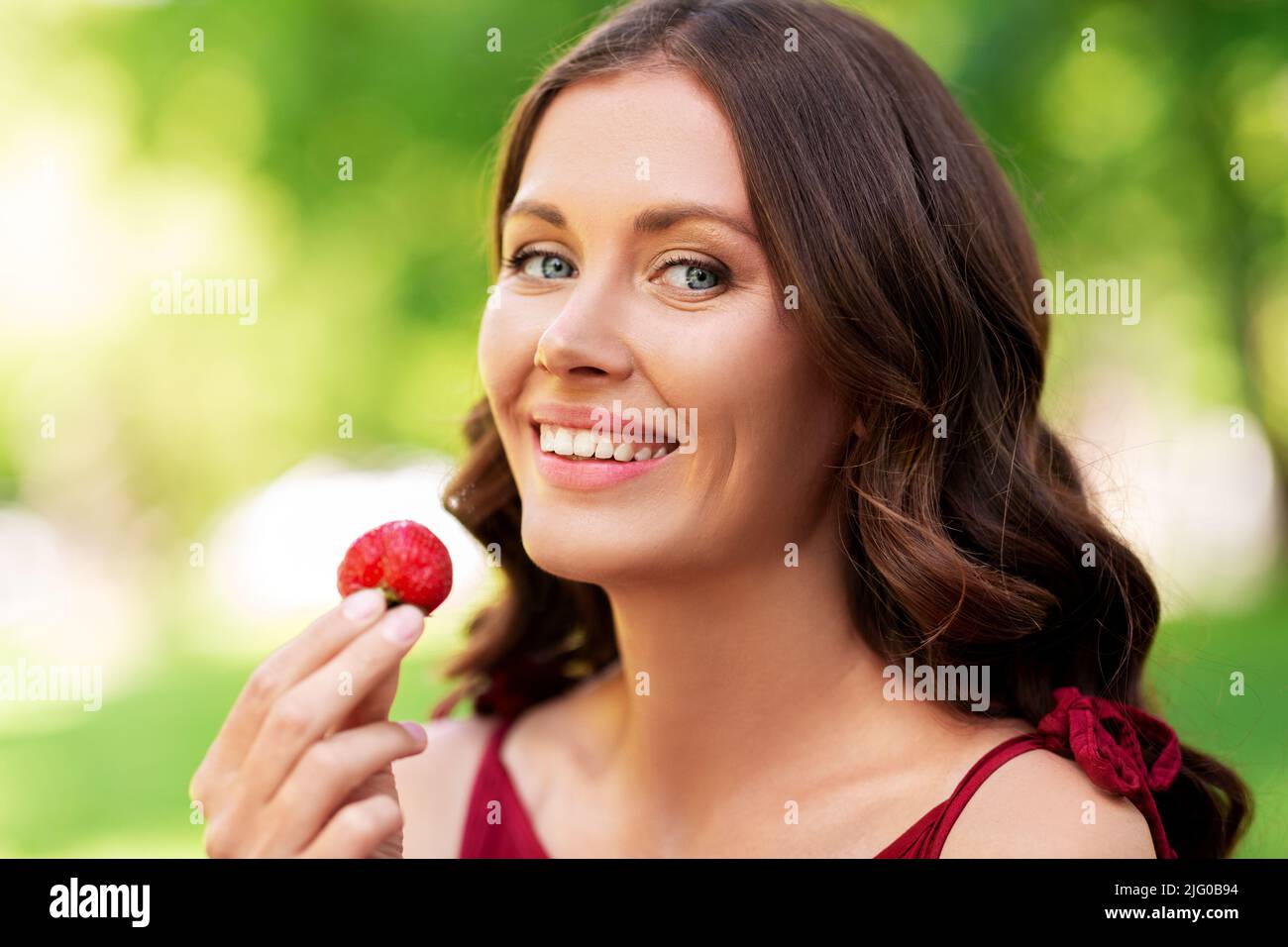 bonne femme mangeant des fraises dans le parc d'été Banque D'Images