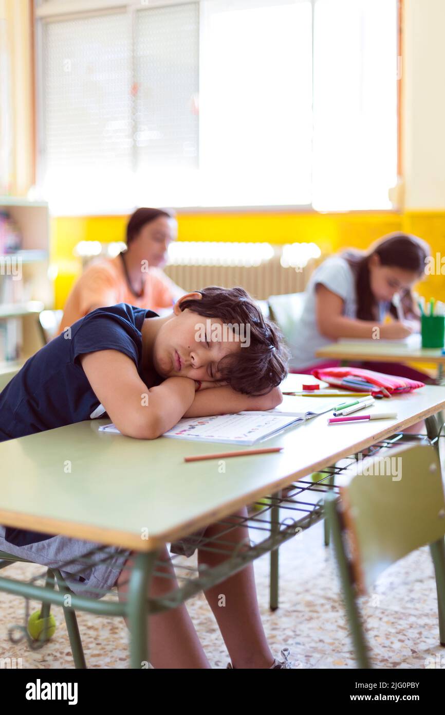 Petit garçon caucasien dormant pendant un cours à l'école. Enseignement primaire. Espace pour le texte. Banque D'Images