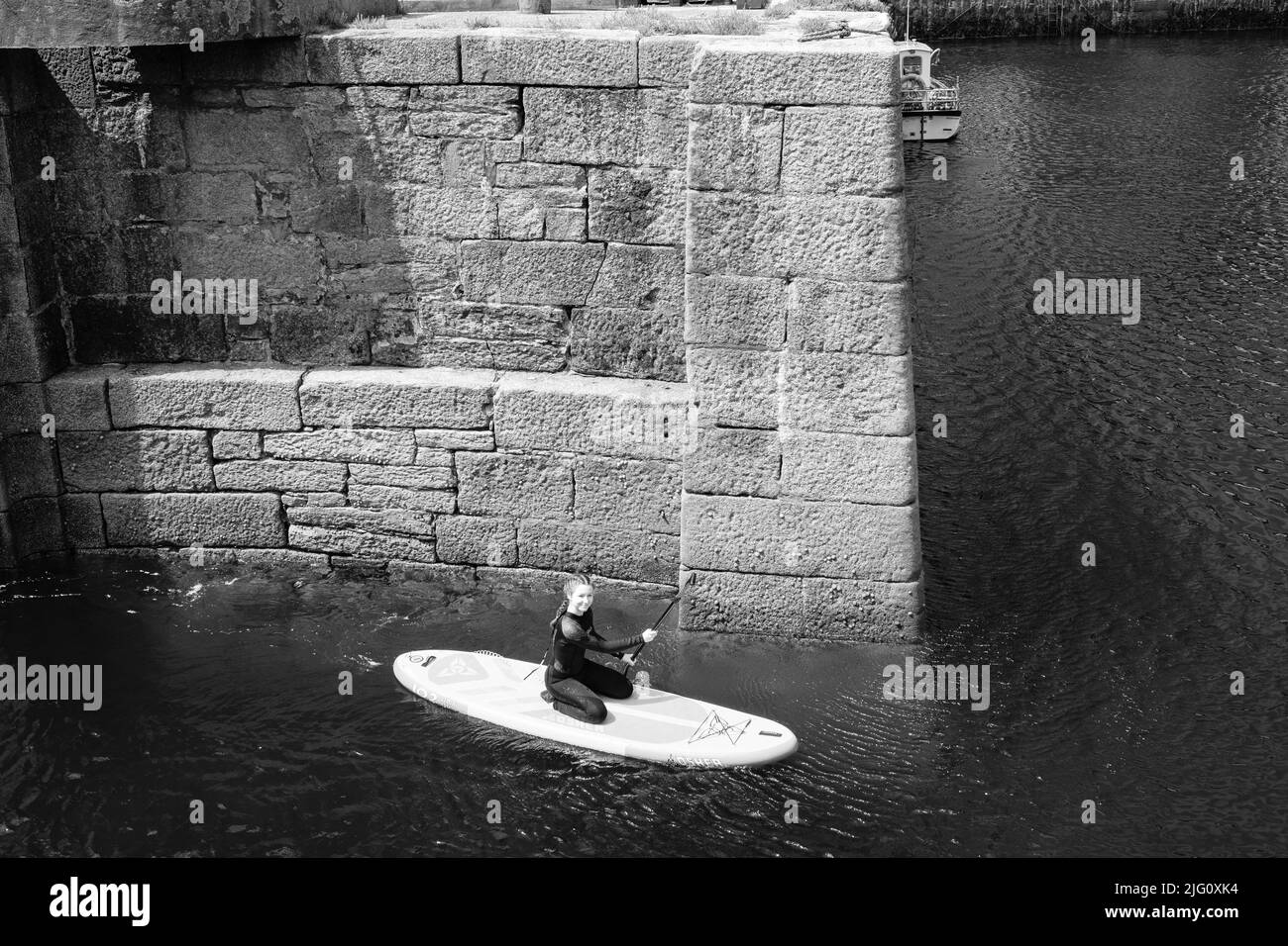 Paddleboard dans le port de Porthleven, Cornouailles Banque D'Images