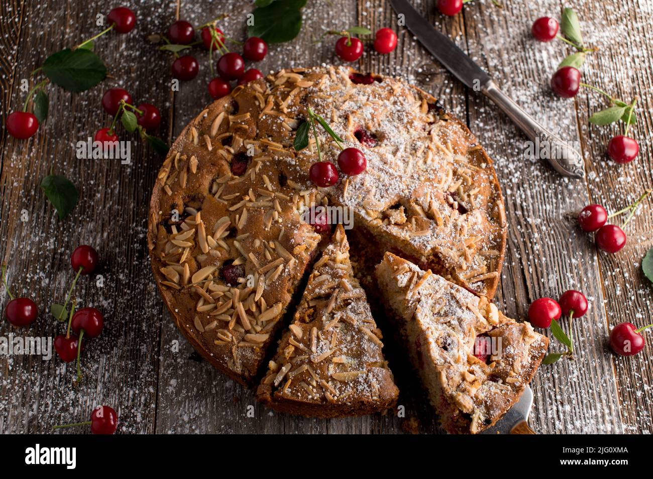 Gâteau à la cerise avec garniture aux amandes sur une table en bois. Cuit avec de la farine de blé entier Banque D'Images