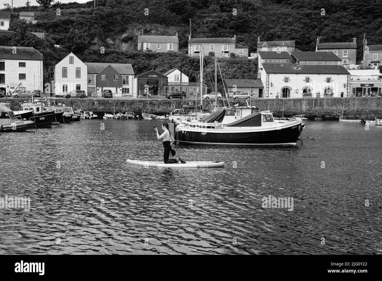 Paddleboard dans le port de Porthleven, Cornouailles Banque D'Images