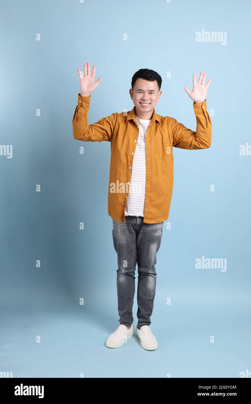 L'homme LGBTQ asiatique avec une chemise jaune sur fond bleu. Banque D'Images