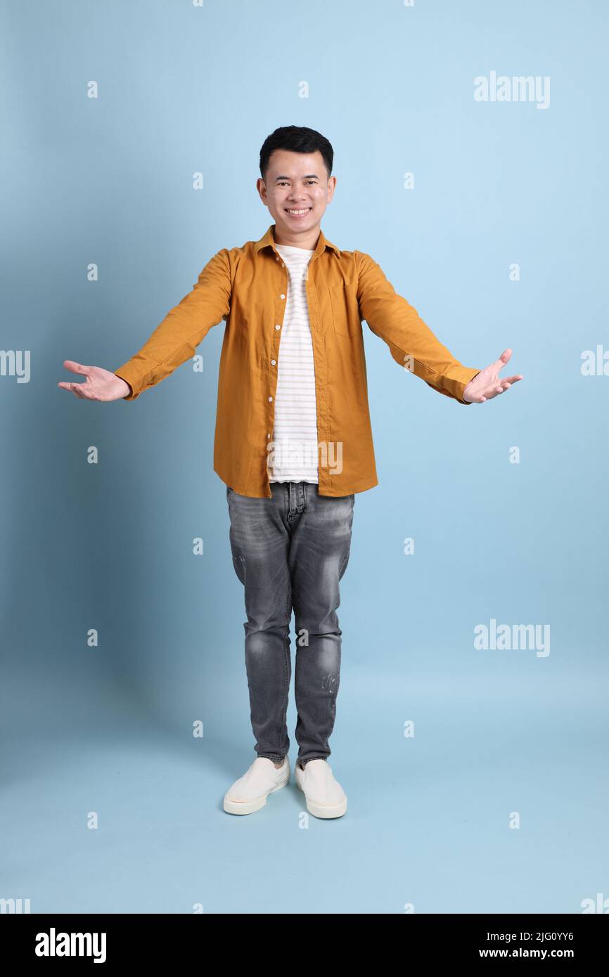 L'homme LGBTQ asiatique avec une chemise jaune sur fond bleu. Banque D'Images
