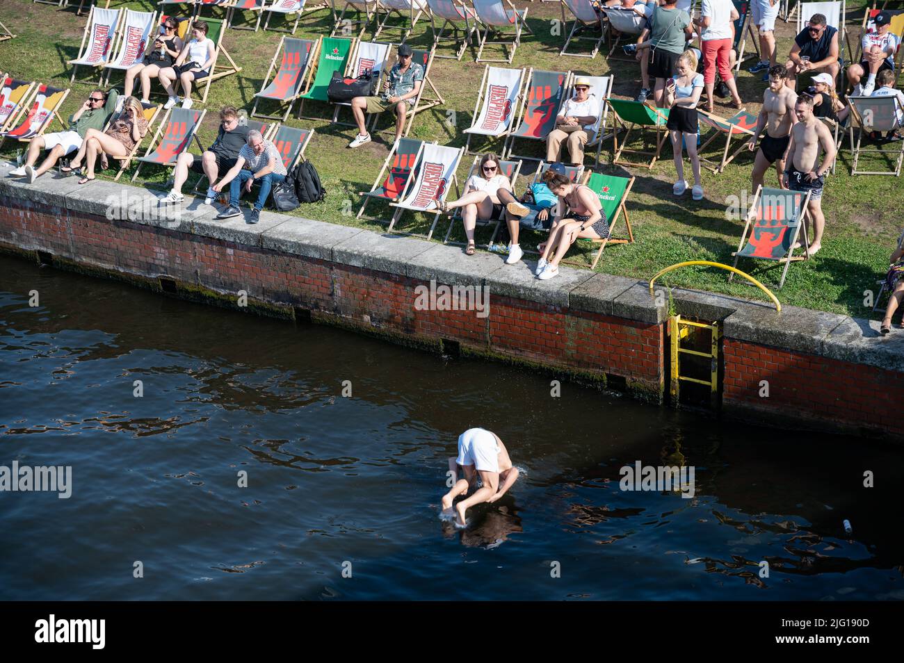 03.07.2022, Berlin, Allemagne, Europe - Un jeune homme saute de la rive du Ludwig-Erhard-Ufer dans la rivière Spree fraîche lors d'une chaude journée d'été. Banque D'Images