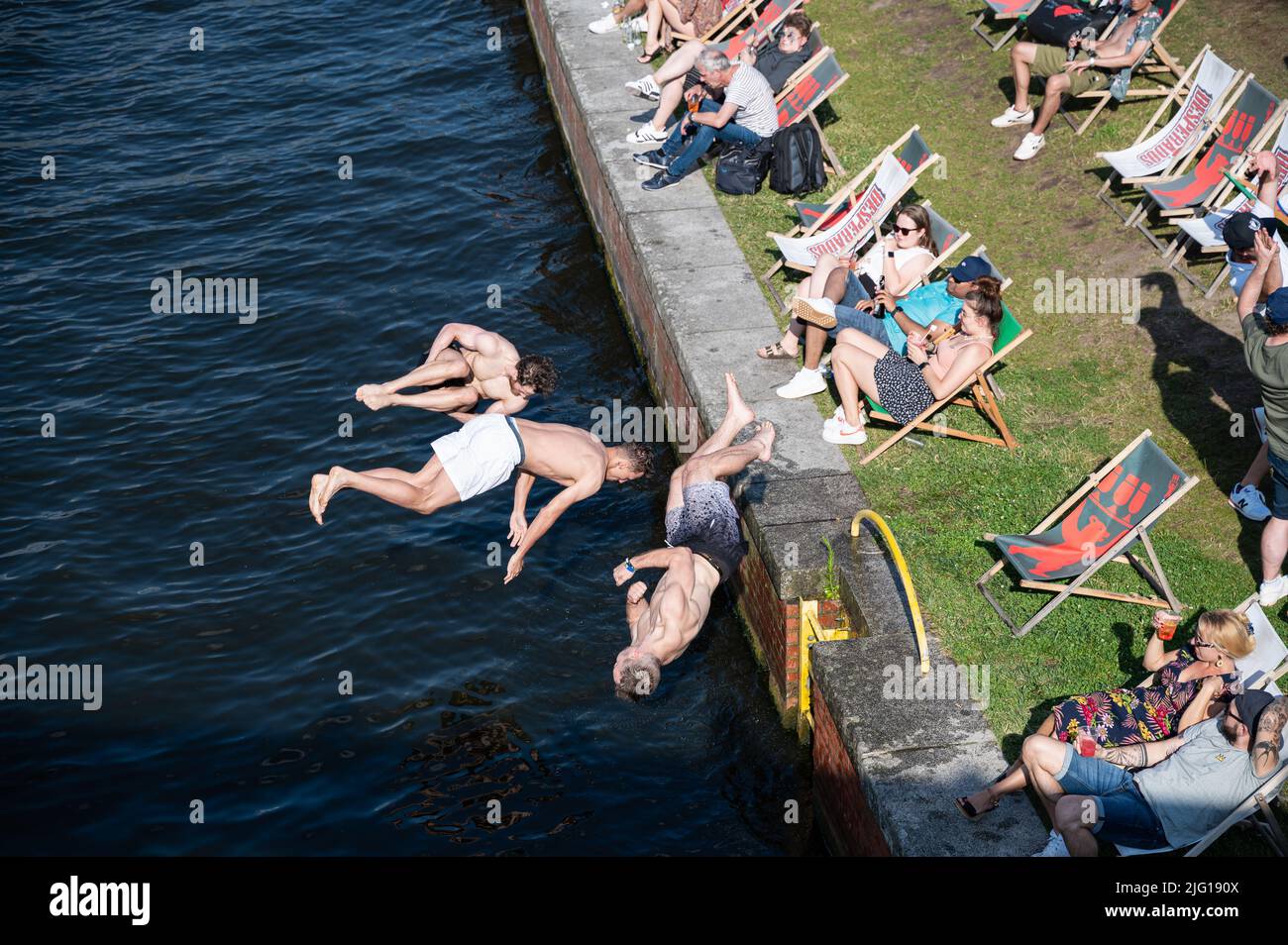 03.07.2022, Berlin, Allemagne, Europe - trois jeunes hommes sautent de la rive du Ludwig-Erhard-Ufer dans la rivière Spree, lors d'une chaude journée d'été. Banque D'Images