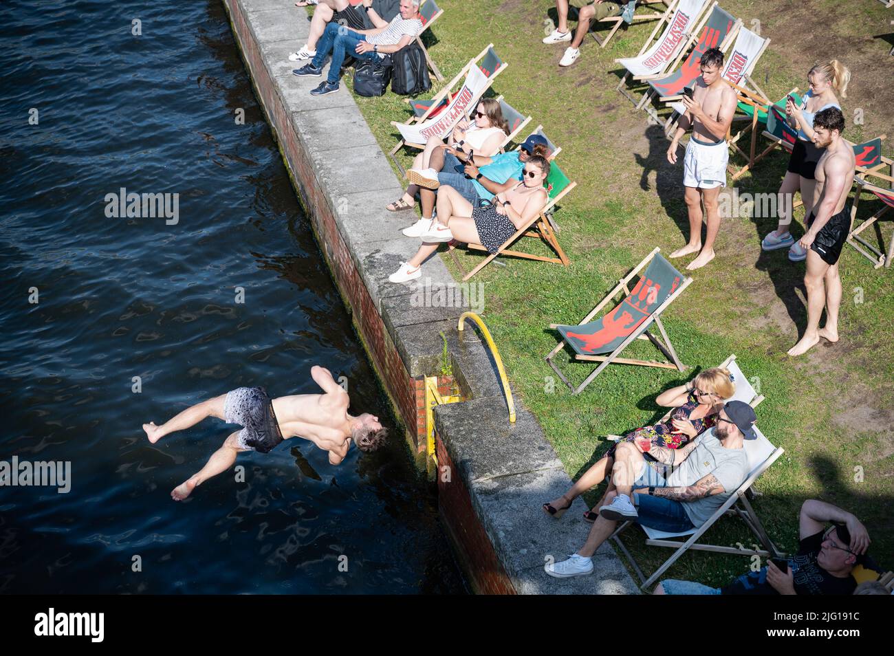 03.07.2022, Berlin, Allemagne, Europe - Un jeune homme saute de la rive du Ludwig-Erhard-Ufer dans la rivière Spree fraîche lors d'une chaude journée d'été. Banque D'Images
