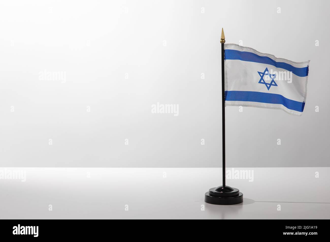 Pays volant drapeau israélien isolé sur une table blanche avec un fond gris Banque D'Images