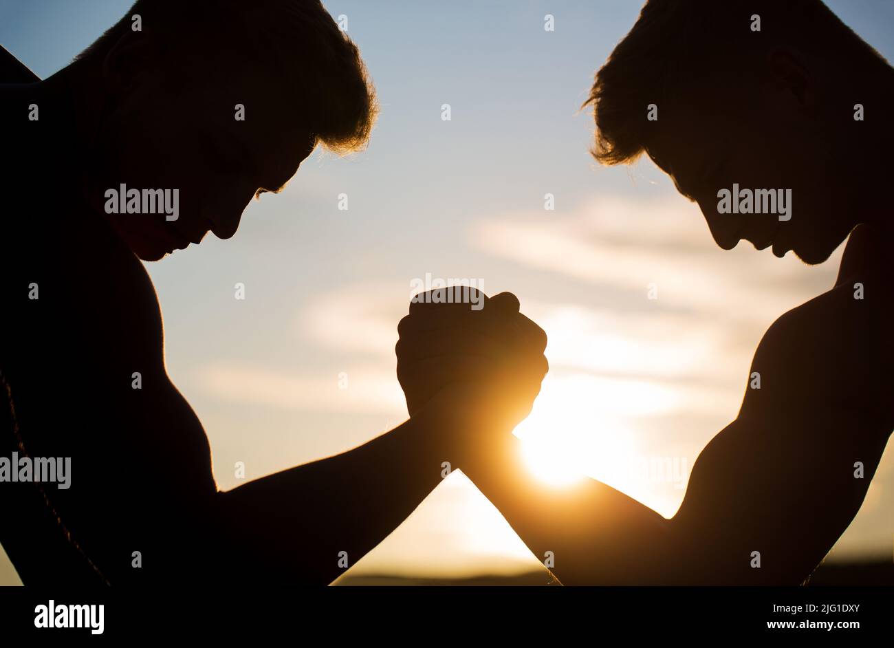 Rivalité, vs, défi, lutte de main. Coucher de soleil, lever du soleil. Rivalité, gros plan de lutte de bras mâle. Hommes mesurant les forces, les bras. Banque D'Images