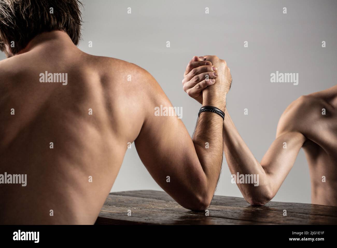 Lutte de bras. Homme barbu fortement musclé bras luttant un homme faible et puny. Bras luttant main mince, gros bras fort en studio. Deux mains d'homme ont classé Banque D'Images