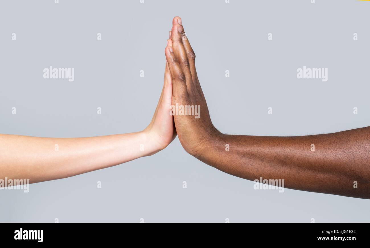 Femme blanche, homme africain donnant cinq hauts, symbole de l'amitié.couple de race mixte tenant les mains. Haut-cinq geste et tendresse de l'amitié entre Banque D'Images