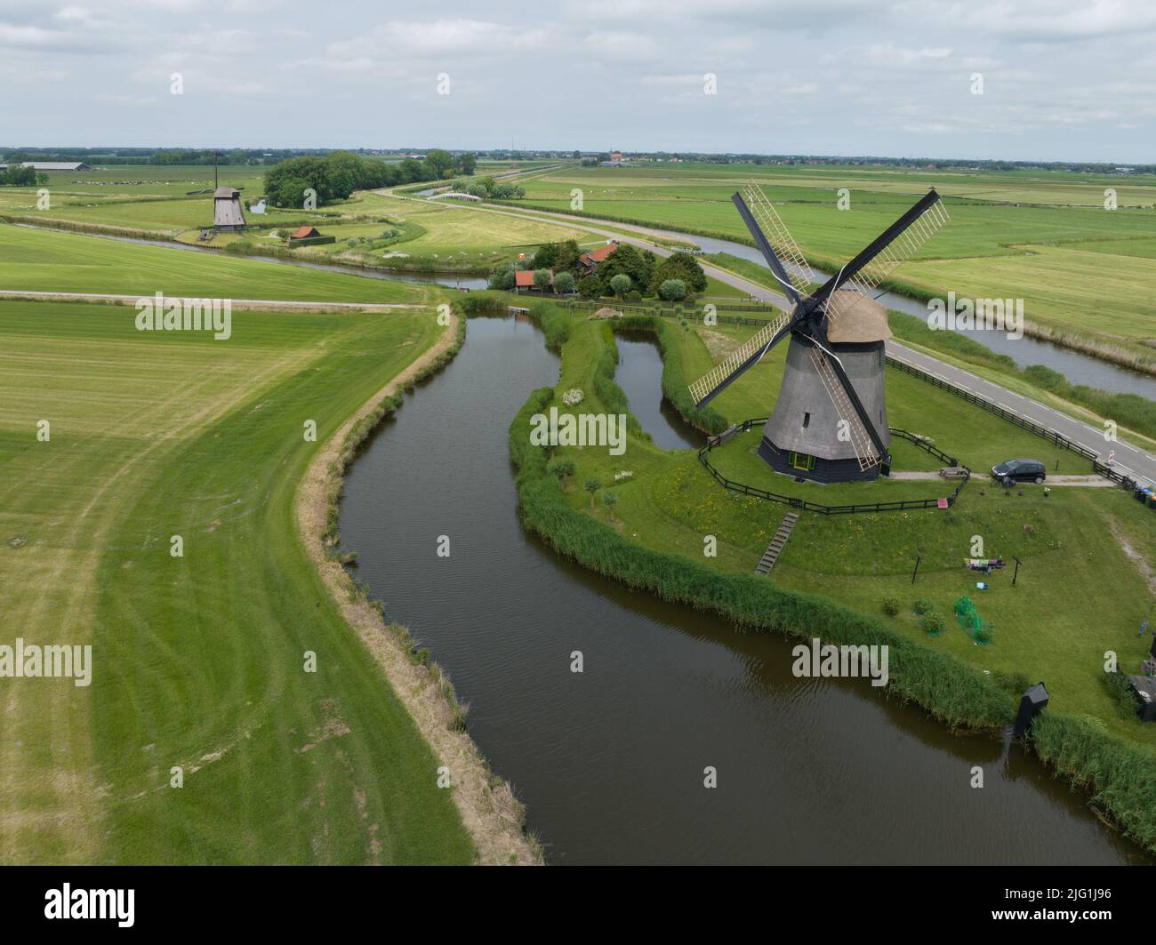 Vieux moulins à vent traditionnels hollandais historiques sur la campagne rurale dans la nature verte paysage de ferme d'herbe avec un temps ensoleillé de rivière Banque D'Images