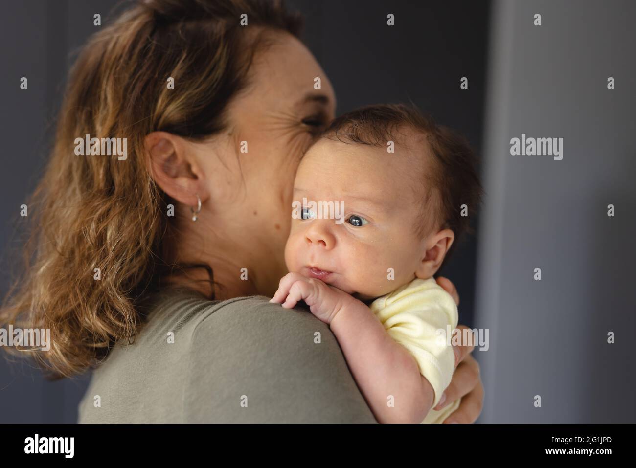Bonne humeur adulte moyen de race blanche mère portant bébé mignon nouveau-né à la maison, espace de copie Banque D'Images