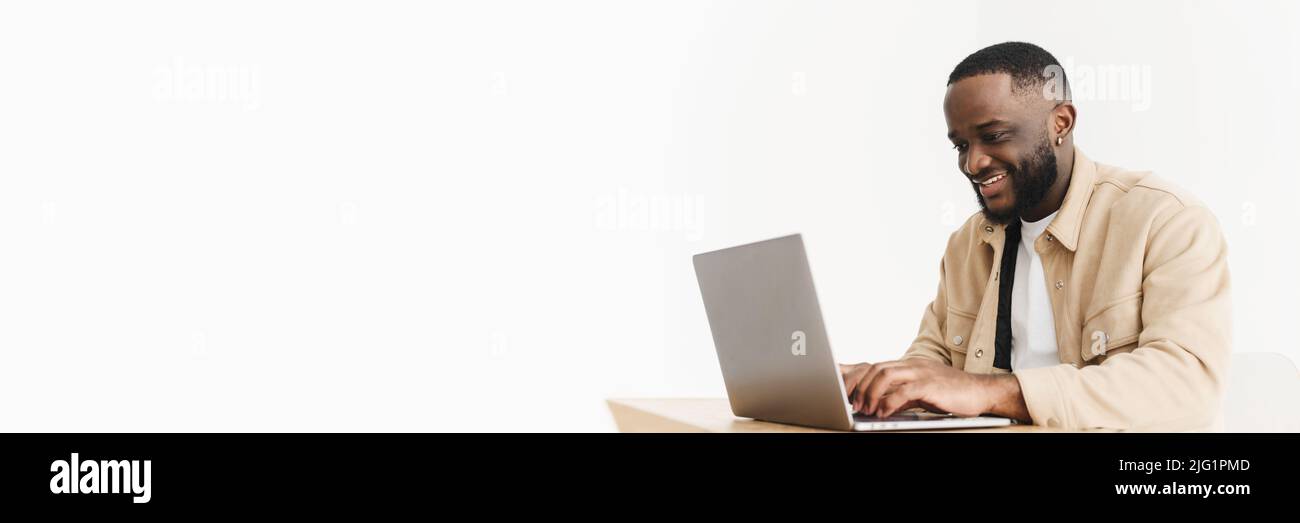 Bannière Web. Professionnel souriant homme d'affaires noir utilisant un ordinateur portable travaillant à domicile. Joyeux travailleur indépendant afro-américain à la maison Banque D'Images