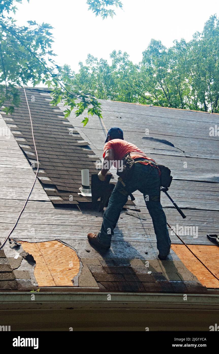 Les couvreurs remplacent l'ancien toit en asphalte d'une maison résidentielle. Banque D'Images