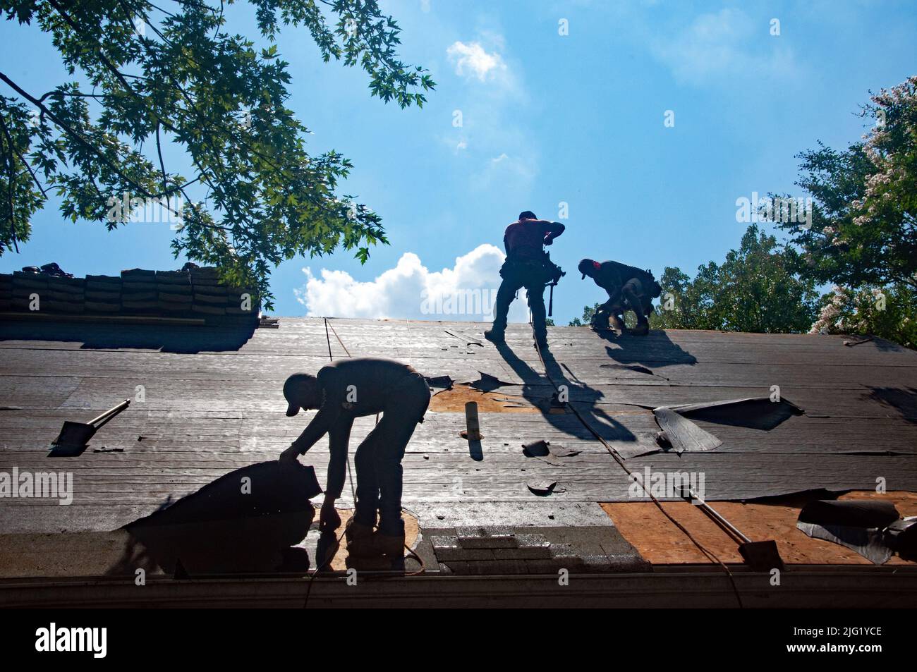 Les couvreurs remplacent l'ancien toit en asphalte d'une maison résidentielle. Banque D'Images