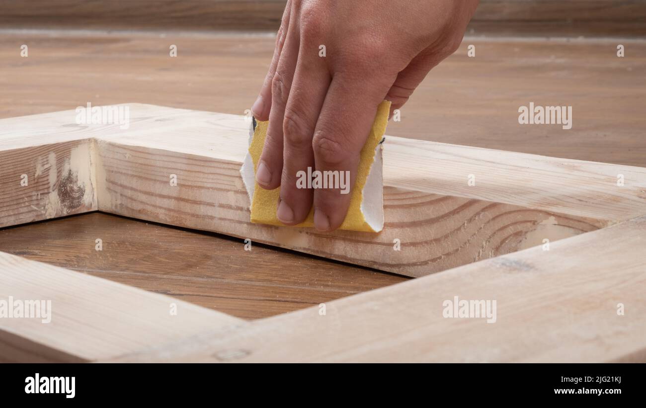 ponçage manuel des portes en bois avec du papier de verre. Banque D'Images