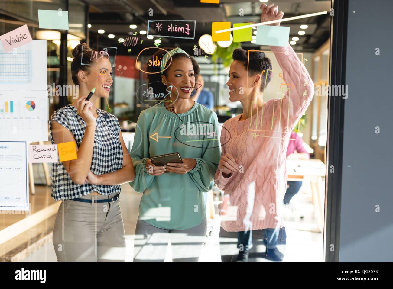 Des collègues multiraciaux discutent de la stratégie d'entreprise sur un mur de verre au bureau Banque D'Images