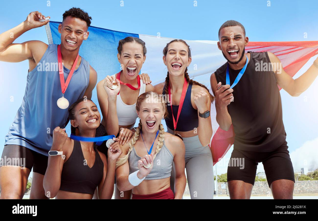 Heureux et fiers athlètes olympiques français célébrant des médailles gagnantes pour leur pays. Portrait d'un groupe diversifié de sportifs avec un drapeau français Banque D'Images