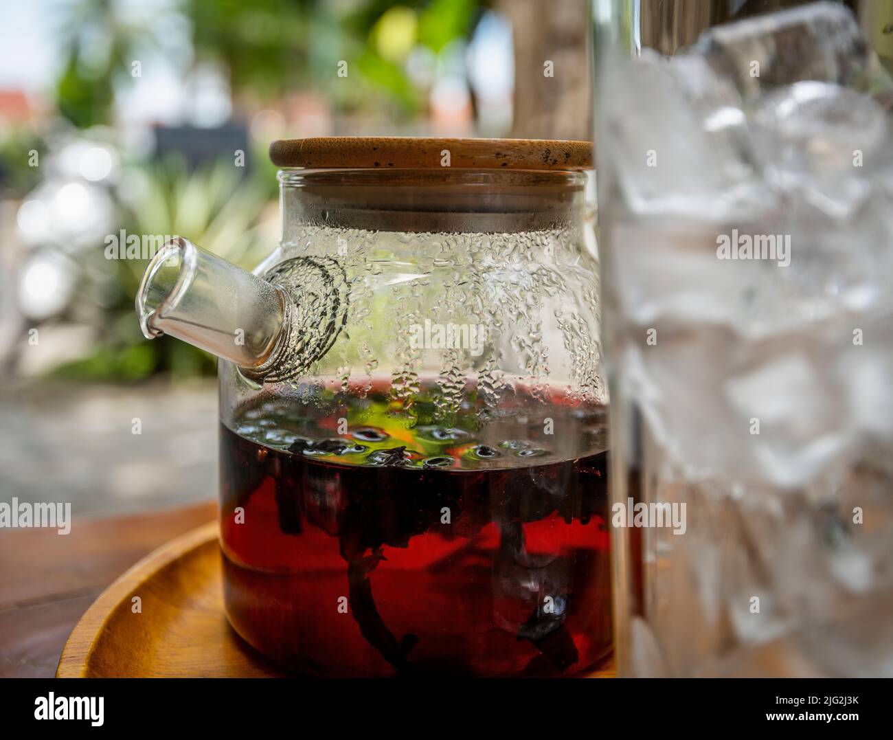 Pot de thé hibiscus braquant à côté d'un grand verre de glace. Banque D'Images
