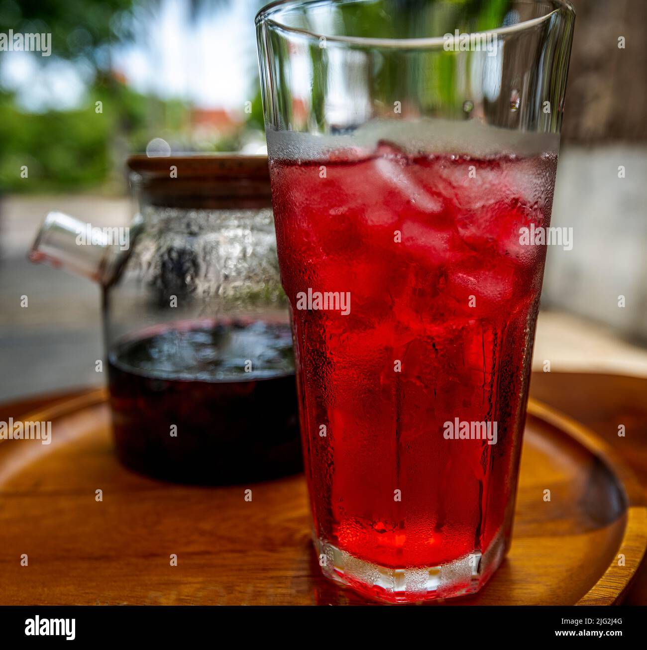 Pot de thé hibiscus braquant à côté d'un grand verre de glace rouge. Banque D'Images