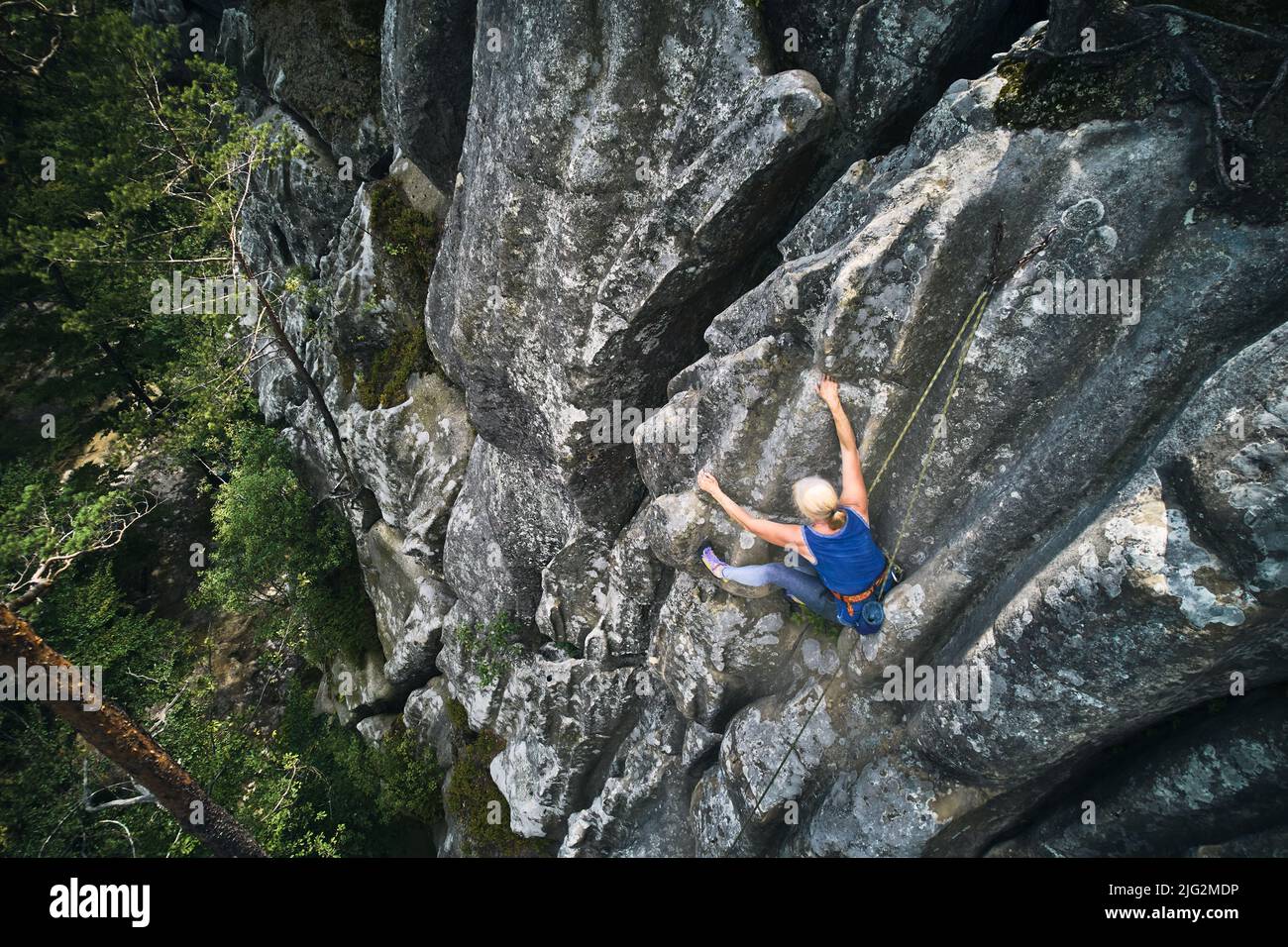 Femme d'alult senior grimpant sur une route difficile sur une roche haute avec corde.Grimpeur sans peur pour l'entraînement de l'escalade le jour de l'été.Concept de sport extrême, d'aventures et de mode de vie actif.Vue aérienne. Banque D'Images