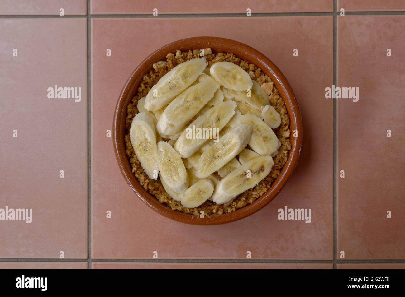 Un délicioius banoffee tarte dans la fabrication, la base de biscuit est dans le plat avec le caramel et les bananes en tranches. Banque D'Images