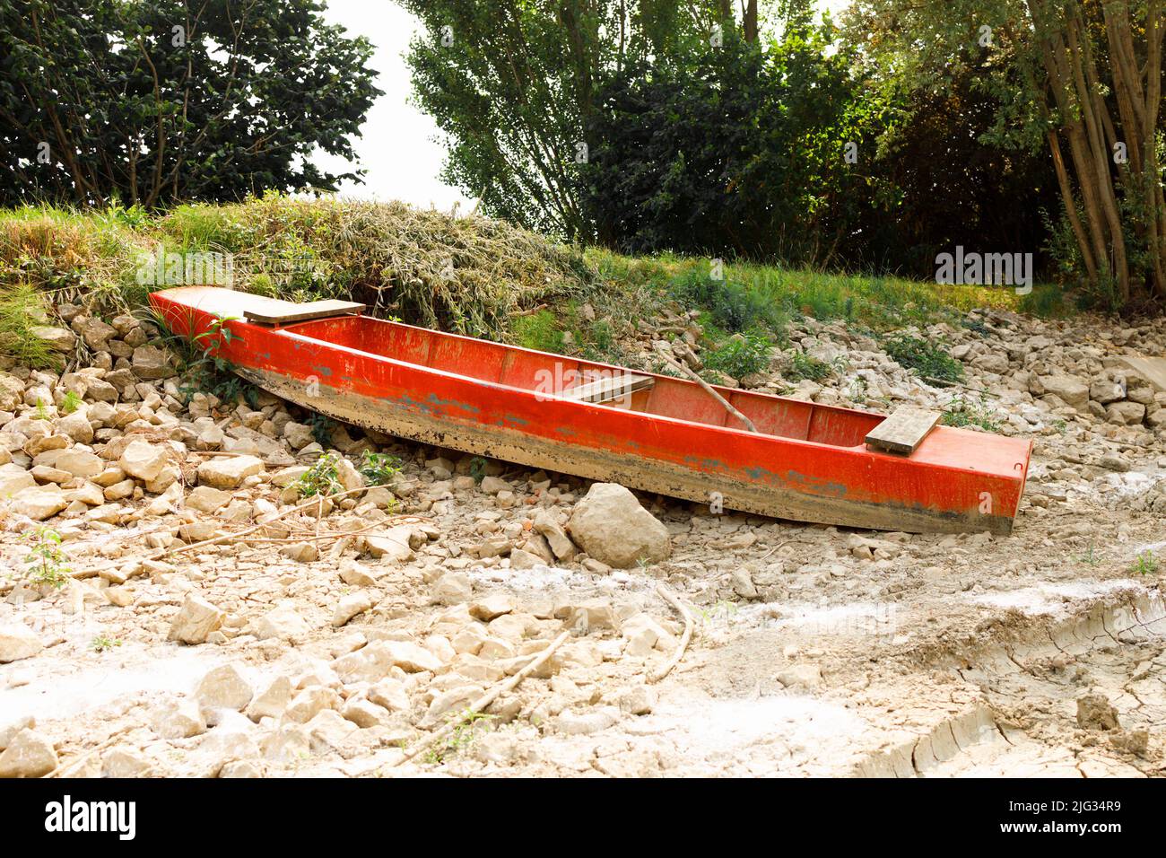 Bateau de pêche sur la rive d'un lac asséché en raison des vagues de chaleur brutales de l'été et du changement climatique Banque D'Images