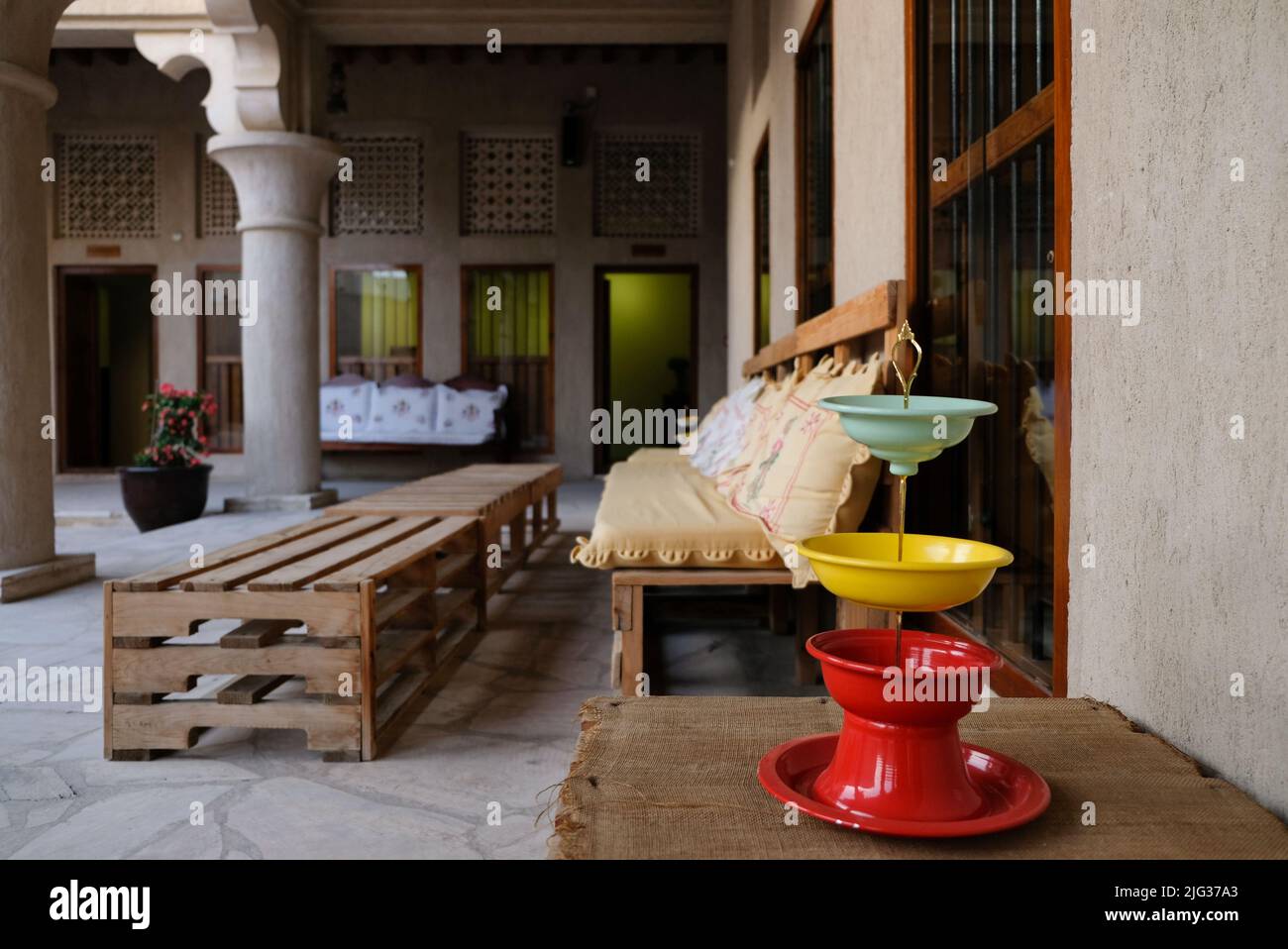 Place assise dans une cour ouverte d'une maison arabe traditionnelle. Chaises en bois et caisses pour tables. Panier de fruits audacieux et coloré au premier plan. Banque D'Images
