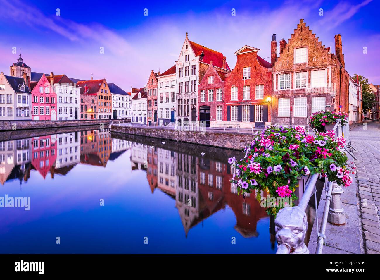 Bruges, Belgique. Paysage de l'heure bleue au lever du soleil avec maisons de réflexion sur l'eau sur le canal de Spiegelrei, célèbre point de repère des Flandres. Banque D'Images