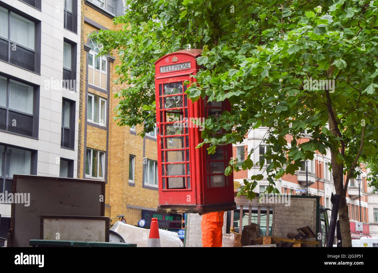 Londres, Royaume-Uni. 7th juillet 2022. Les employés retirent un ancien boîtier téléphonique rouge cassé dans le West End de Londres. Banque D'Images