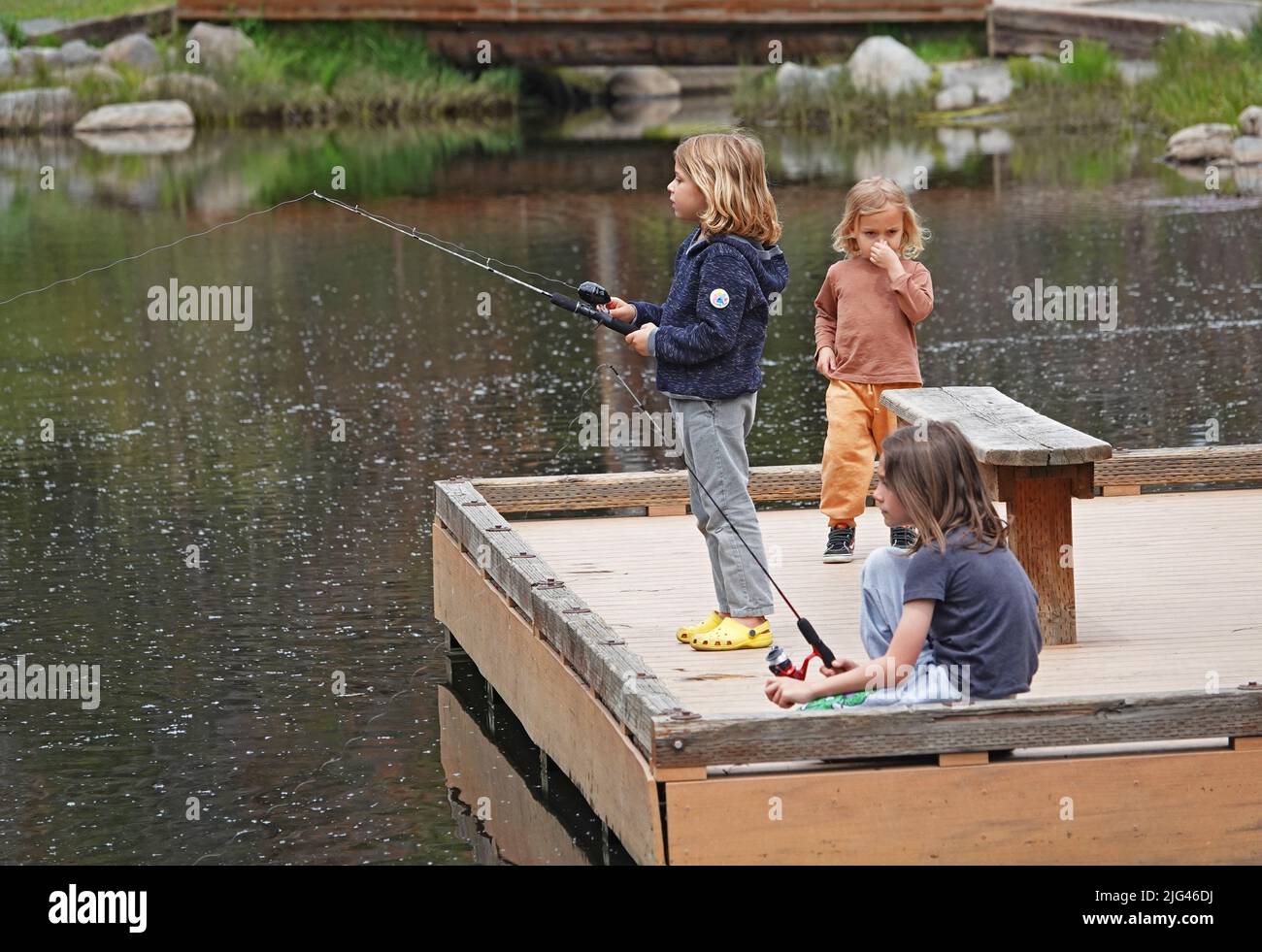 Un groupe de jeunes garçons et filles explorent et pêchent autour d'un petit étang au début de l'été à Bend, Oregon. Banque D'Images