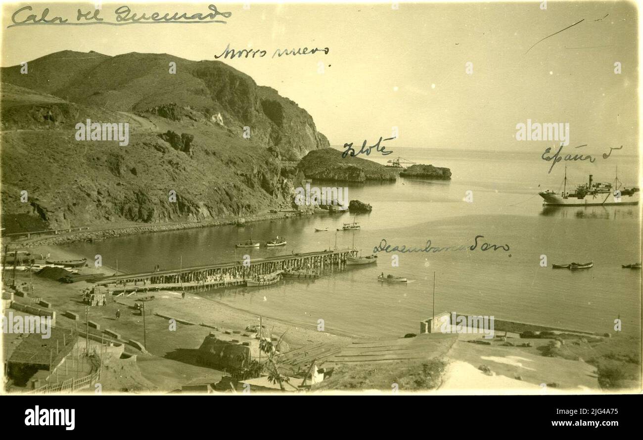 Photographie historique de la crique brûlée dans le rif, 1930. Vue panoramique de la crique brûlée, dans le rif. La jetée se distingue et un gros navire de guerre ancrage. Banque D'Images