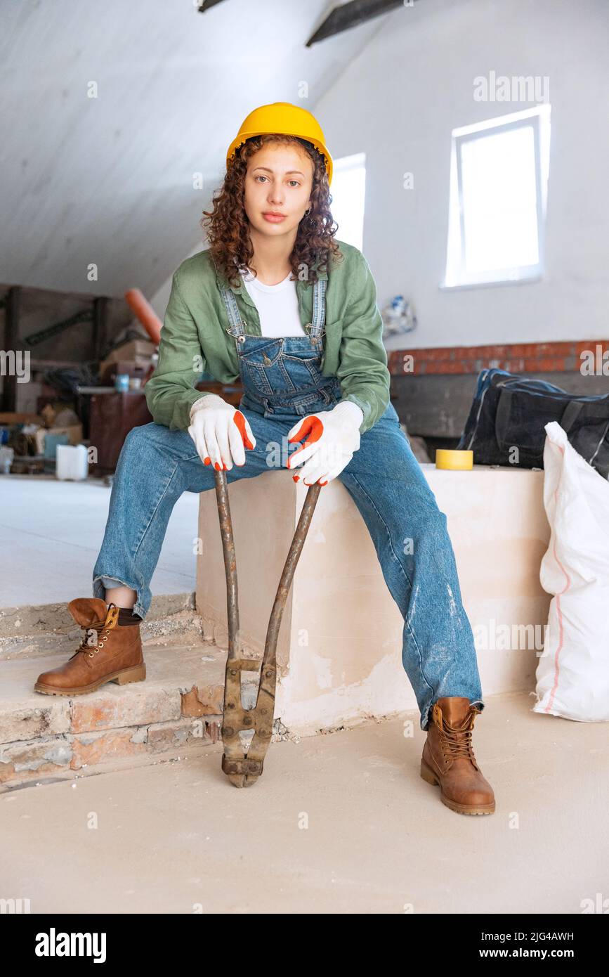 Portrait en direct d'une jeune femme, constructeur portant un casque posé sur un chantier de construction. Égalité des sexes, travail, concept de travail Banque D'Images