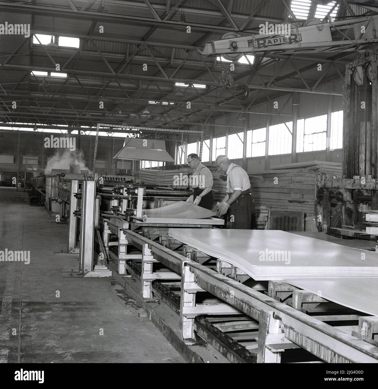 1950s, historique, deux sidérurgistes manipulant des tôles d'acier finies à l'aciérie Steel Company of Wales Abbey à Port Talbot, pays de Galles. ROYAUME-UNI. L'acier pressé et l'acier en fer blanc pour usage domestique et la fabrication de voitures automobiles étaient tous deux des produits de ces géants industriels. Banque D'Images