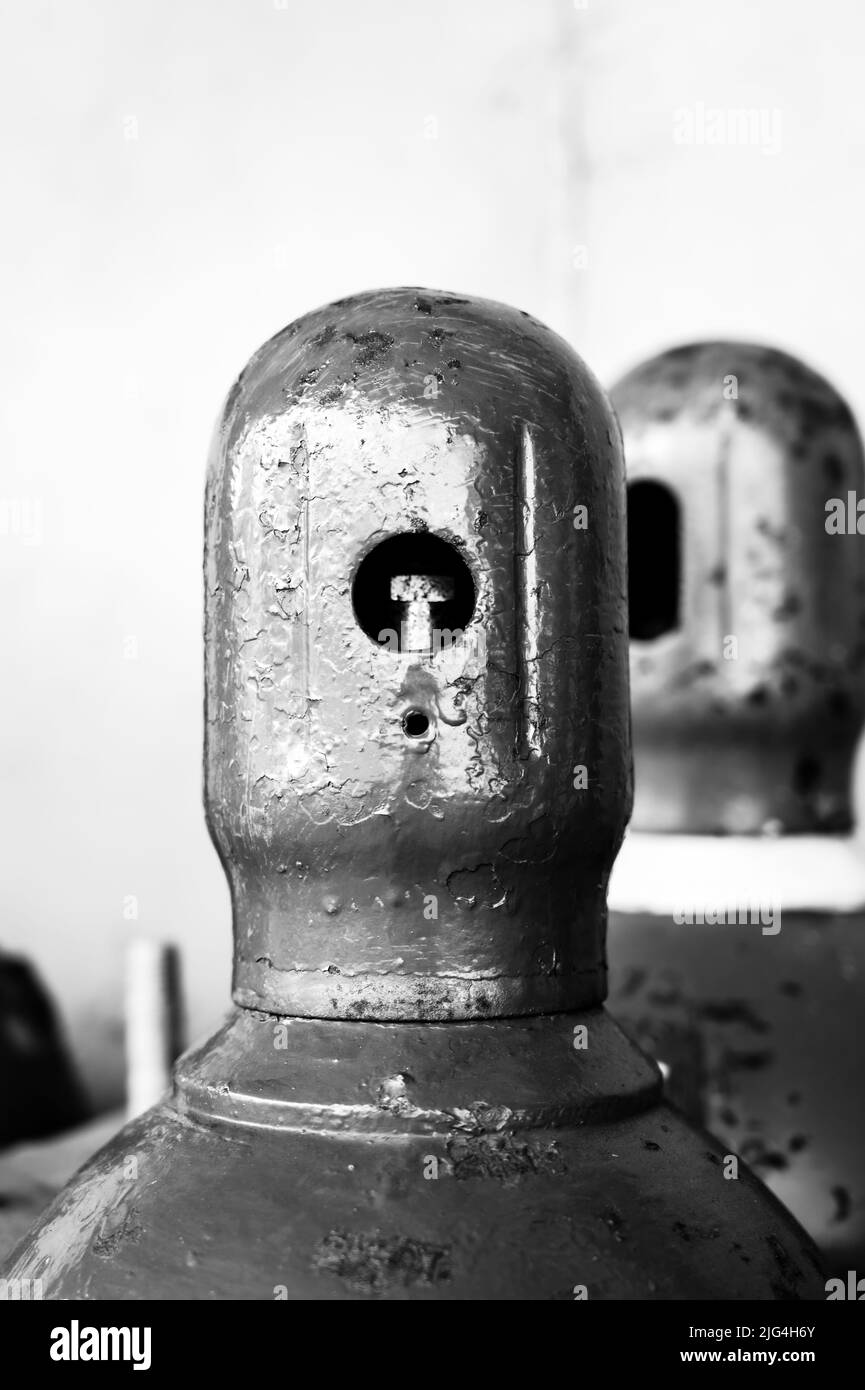 Bouteilles de gaz comprimé stockées verticalement fixées par une chaîne métallique et un bouchon en métal. Banque D'Images