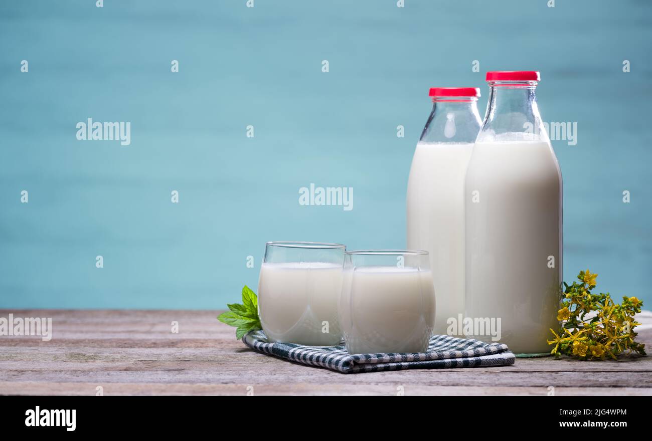 Deux verres et deux bouteilles de lait sur table en bois avec fond en bois bleu clair. Banque D'Images