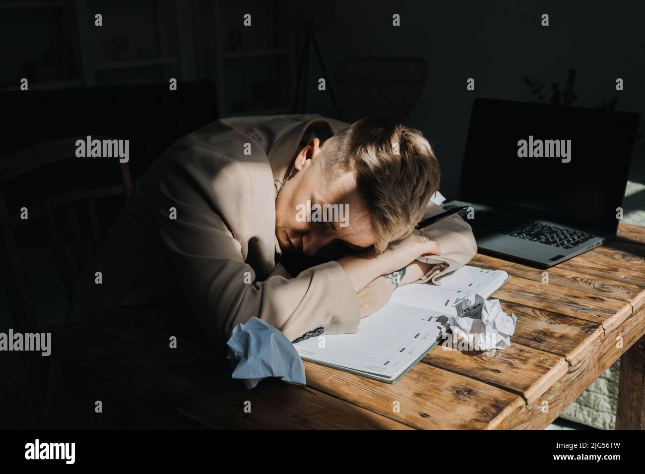 Épuisement, problèmes émotionnels, concept de dépression. Triste femme dépressive fatiguée couchée sur la table parmi les papiers Banque D'Images