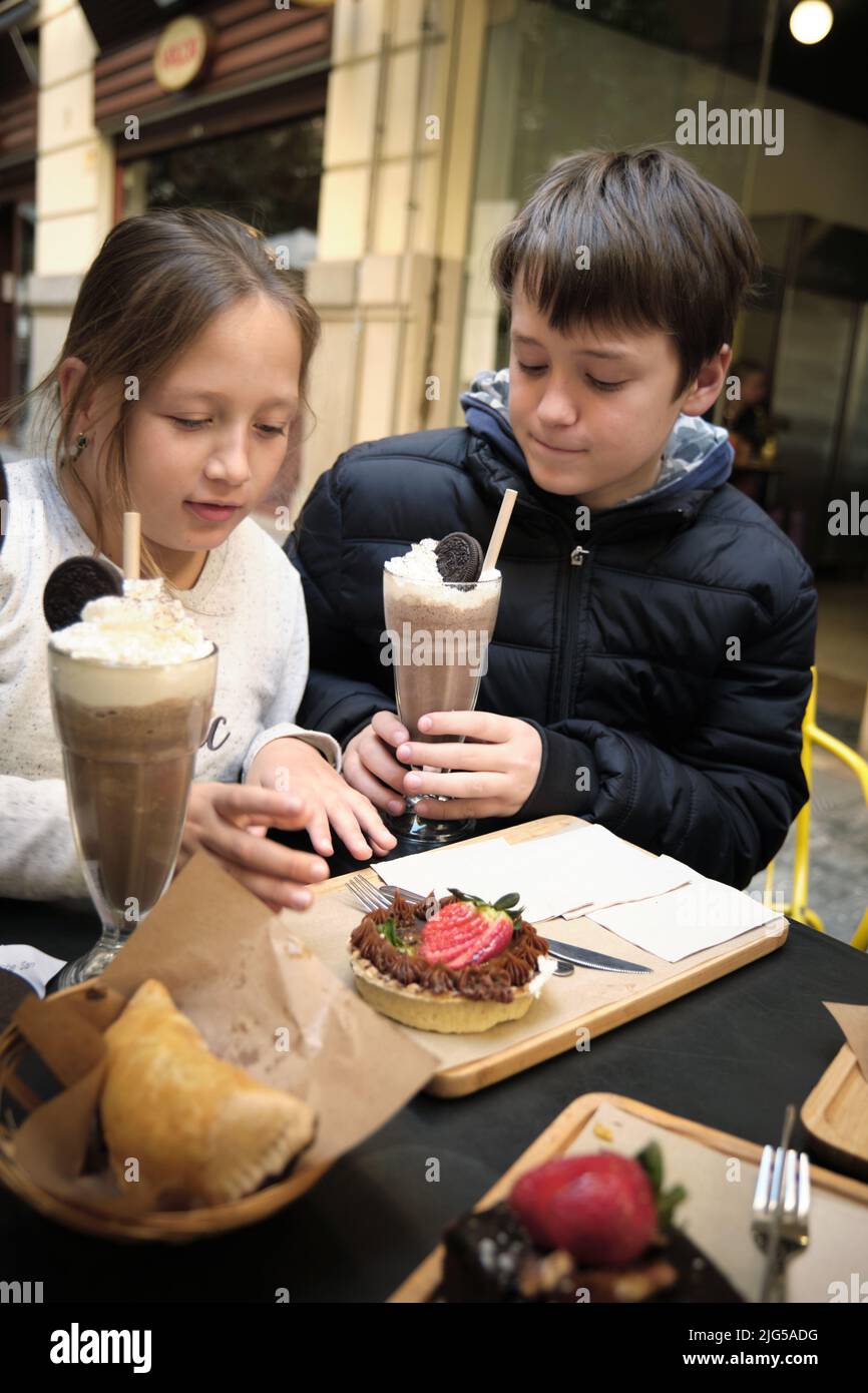 un garçon et une fille avec un milkshake et un gâteau Banque D'Images