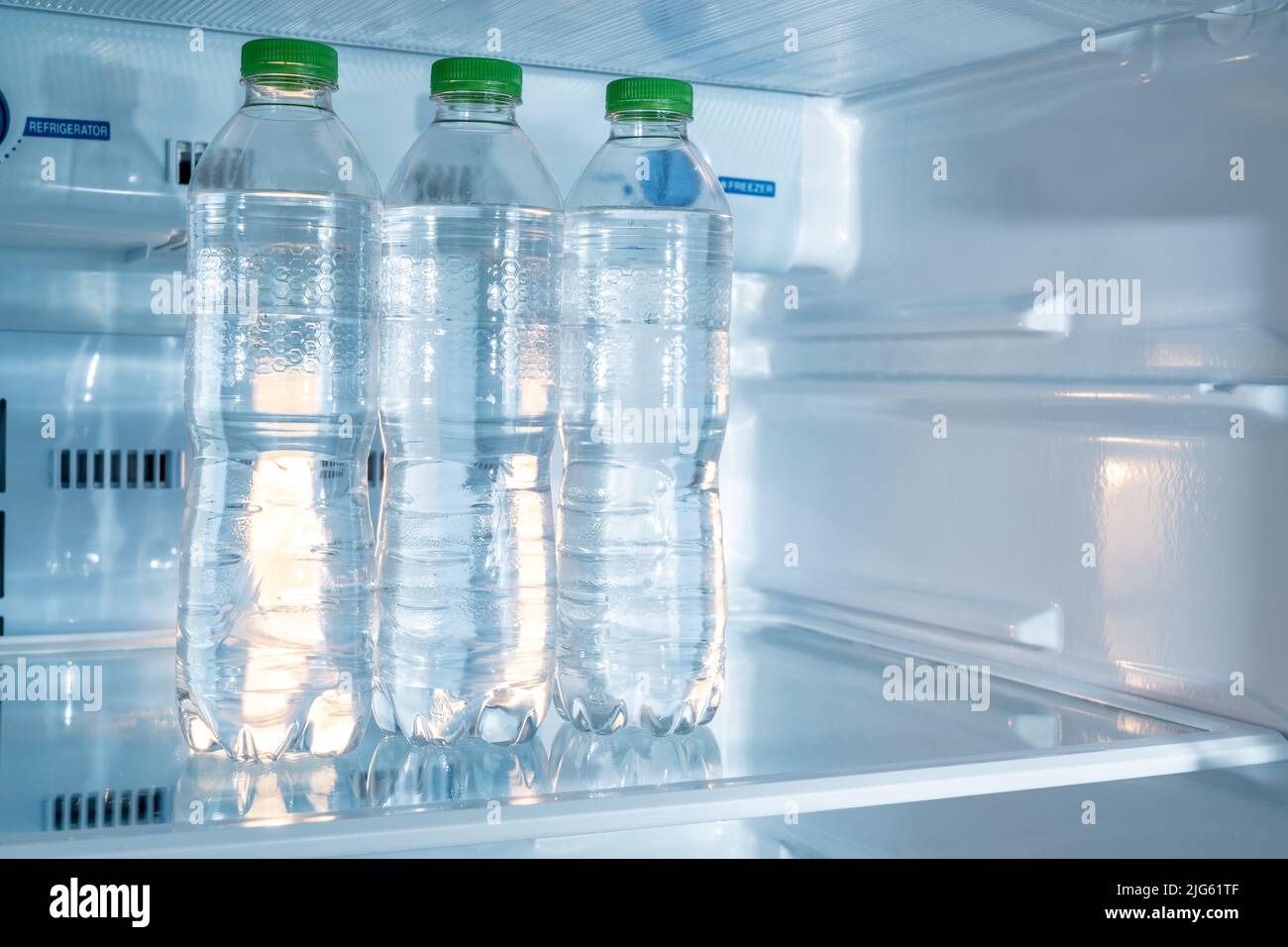 Bouteilles froides d'eau potable propre dans un réfrigérateur blanc Banque D'Images