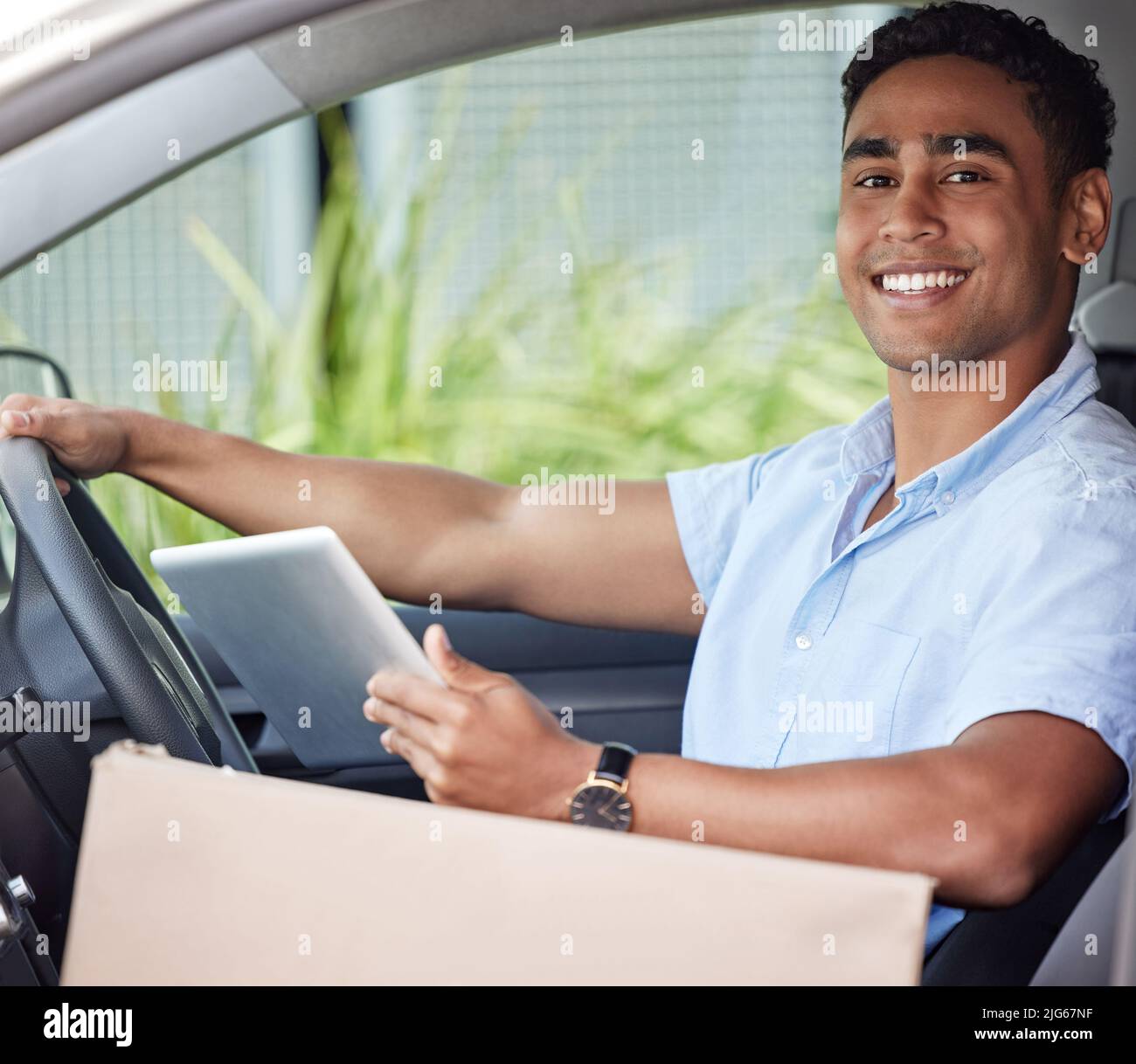 Je vous offre ensuite votre forfait. Portrait d'un jeune liveur utilisant une tablette numérique assis dans une camionnette. Banque D'Images