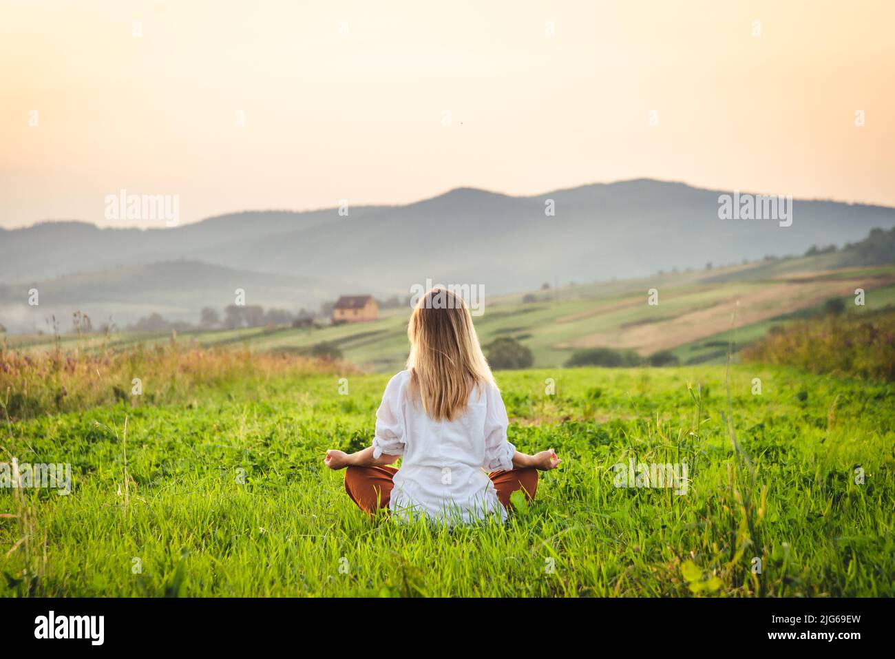 Femme faisant du yoga sur l'herbe verte à la montagne. Carpates Banque D'Images