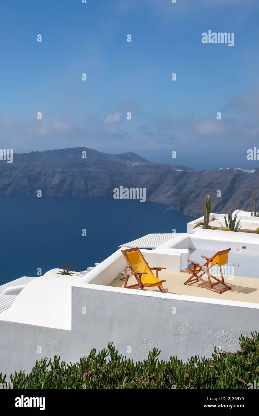 Vue sur deux chaises longues vides sur le toit d'une villa et vue spectaculaire sur la mer Égée à Santorini Grèce Banque D'Images